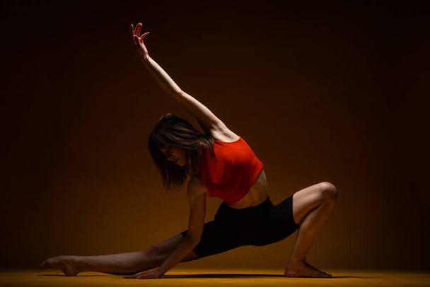 Bailarina está esteretizando en el suelo mientras posa sobre el fondo amarillo - Foto, imagen