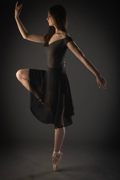 Kaunis ballerina poseeraa tasapainottaessaan yhdellä jalalla. - Valokuva, kuva