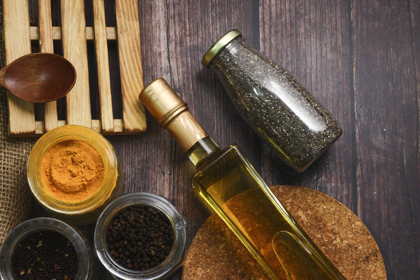 A top view of a bottle of oil, various seasonings, chopping boards and a wooden spoon a table - Photo, Image