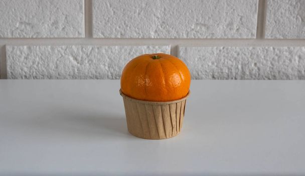 Molde de bolo de papel com tangerina em um fundo branco. O conceito de uma dieta saudável e uma vida amiga do ambiente. - Foto, Imagem