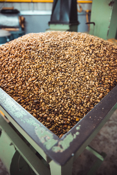 A vertical shot of a big coffee roasting device full of coffee beans - Fotó, kép