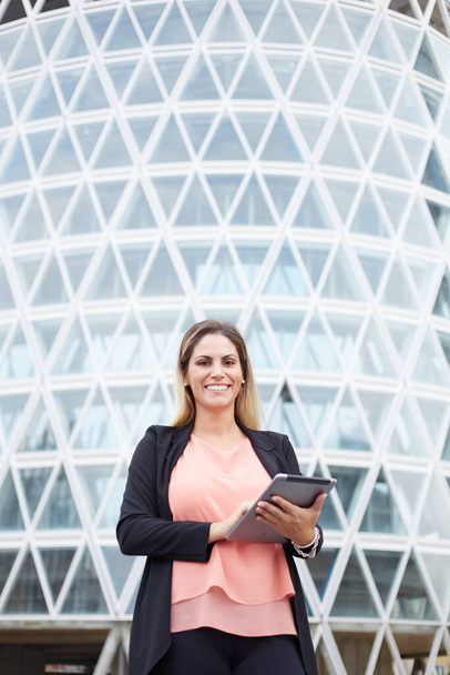 Smiling businesswoman holding digital tablet in urban environment - Photo, Image