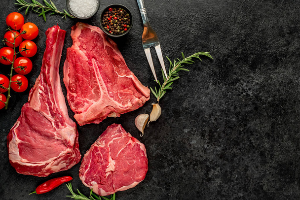 raw beef steak with spices and herbs on black background - Φωτογραφία, εικόνα