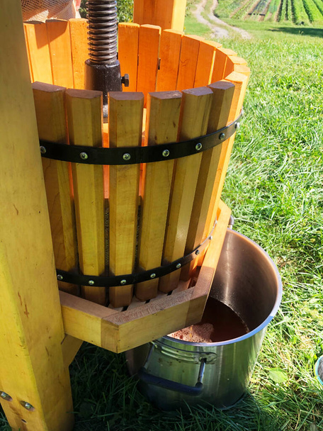 Una olla de cocción captura sidra fresca mientras fluye de la prensa de madera. - Foto, Imagen