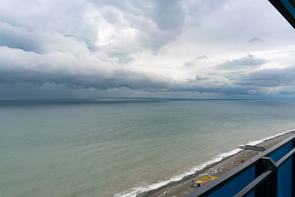 Vue sur la mer depuis le balcon d'un immeuble de grande hauteur pendant la tempête et la pluie sous un ciel nuageux - Photo, image