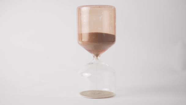 Sand slowly pours in the hourglass on a white background - Footage, Video