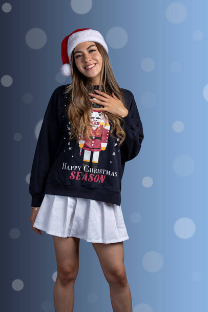 Ritratto di giovane donna latina con maglione natalizio e cappello di Babbo Natale - Foto, immagini