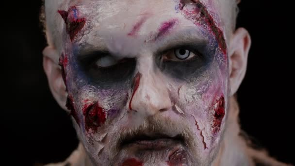 Creepy man scary wounded bloody scars face Halloween undead guy blows smoke from nose, smiles - Footage, Video