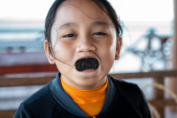 Ik hou van koekjes, Aziatisch meisje met een mond vol koekjes.. - Foto, afbeelding