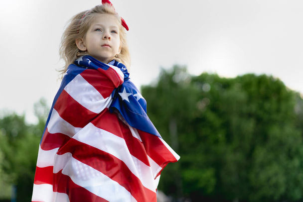 niña con la bandera americana en la naturaleza, el concepto de patriotismo y la fiesta de la independencia de EE.UU.. Día de los Veteranos Estados Unidos. - Foto, imagen