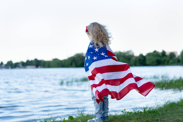 little girl with the American flag in nature, the concept of patriotism and the holiday of independence USA. Veterans Day USA. - Fotografie, Obrázek
