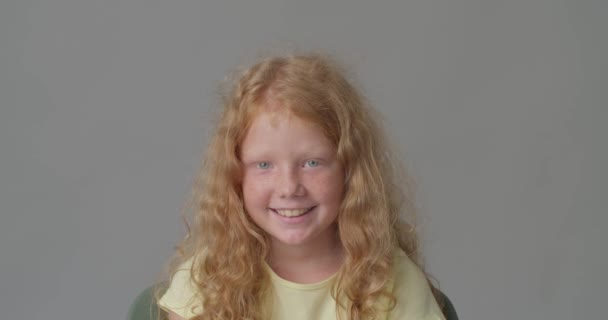 Onnellinen hymyilevä punapää tyttö harmaalla taustalla - Materiaali, video