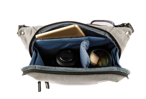 Isolated close up studio shot of small photographer modern fashionable gray shockproof waist bag soft compartment fanny pack carry digital dslr camera len and smartphone inside on white background. - Photo, Image