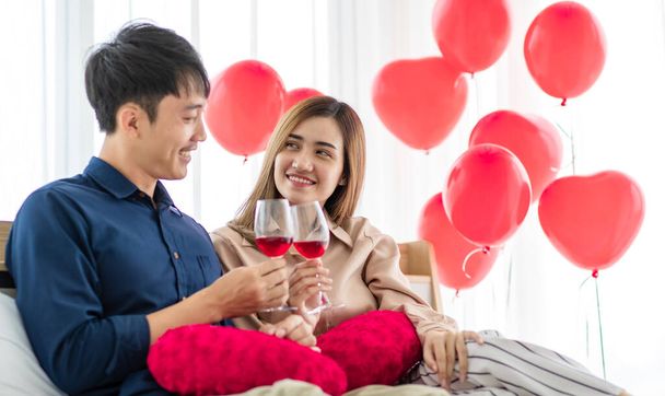自宅でバレンタインデーにロマンチックなデート中にワインの喜びの若い男性と女性の笑いとクリンクグラス.幸せと暖かい関係ov愛好家の概念. - 写真・画像
