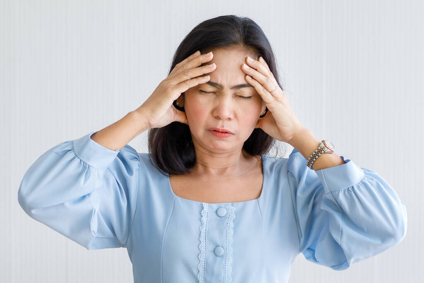 中年アジアの女性は痛みを感じ、突然の頭痛や脳梗塞に苦しみ、顔に苦しむ彼女の頭を保持します。脳と頭の問題の概念. - 写真・画像