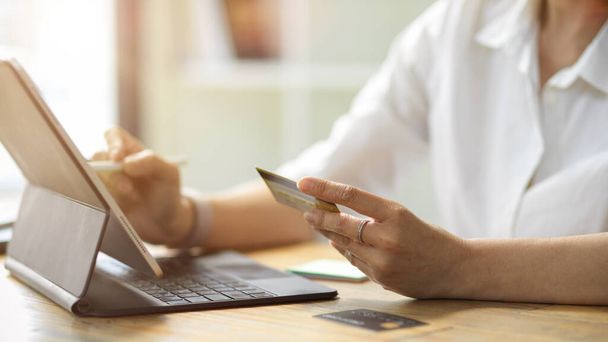 Zbliżenie Dorosła kobieta posiadająca kartę kredytową i zalogować się na swoim internetowym rachunku bankowym za pomocą tabletu cyfrowego do płatności online - Zdjęcie, obraz