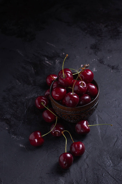 Organic juicy cherry in a bowl on dark background. Close-up photo, low key - Photo, image