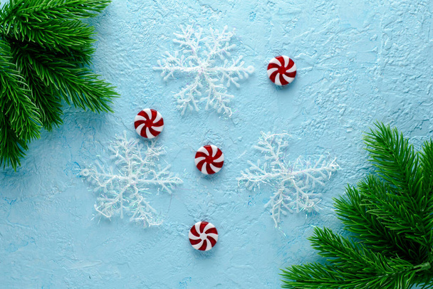 Weihnachtsblauer Hintergrund mit Tannenzweigen, Bonbons und Schneeflocken. Hochwertiges Foto - Foto, Bild