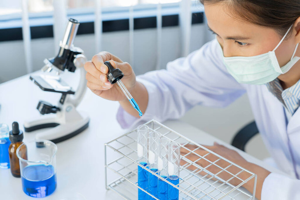 Scientist wear lab coat and protective wear are working with research or doing investigations with test tubes in experiment, Laboratory and development concept. - Photo, image