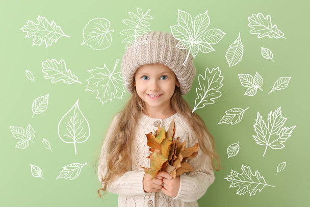 Cute little girl with autumn leaves on color background. Autumn concept - 写真・画像