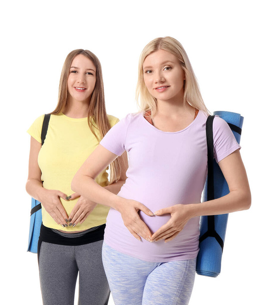 Young pregnant women with yoga mats on white background - Fotoğraf, Görsel