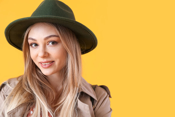 Retrato de una joven sonriente con sombrero de fieltro sobre fondo amarillo - Foto, Imagen