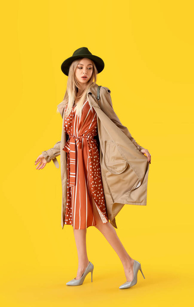 Fashionable woman in stylish shoes and felt hat on yellow background - Foto, Imagen