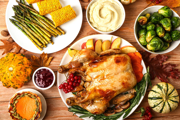 Sabroso pavo al horno y diferentes alimentos para el Día de Acción de Gracias sobre fondo de madera - Foto, Imagen