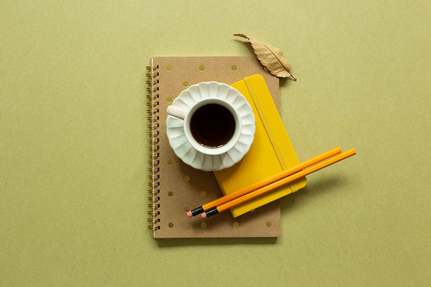 Caderno, xícara de café, lápis sobre fundo cáqui. espaço de trabalho. flat lay, vista superior, espaço de cópia - Foto, Imagem
