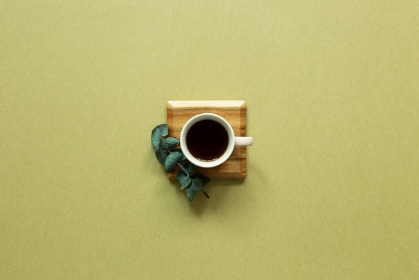 Xícara de café com folha de eucalipto em fundo cáqui. vista superior, espaço de cópia - Foto, Imagem