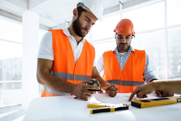 Two engineers man looking at project plan on the table in construction site - Foto, Imagem
