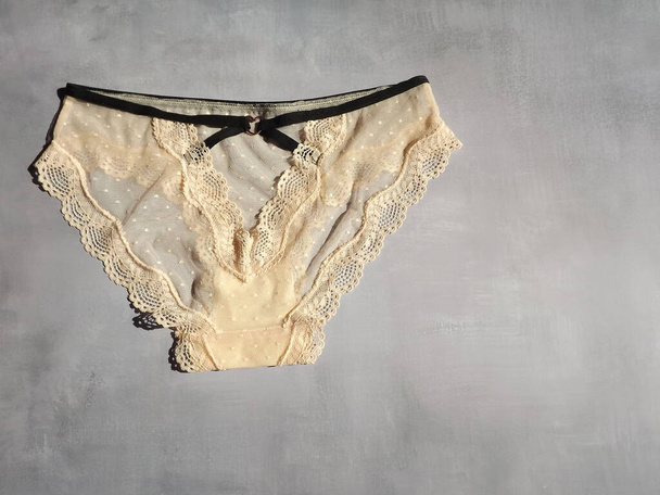 Womens sexy lace panties in peach color on a gray background in the form of a layout - Fotó, kép