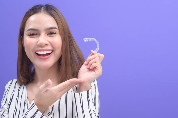 A young smiling woman holding invisalign braces in studio, dental healthcare and Orthodontic concept.	 - Φωτογραφία, εικόνα