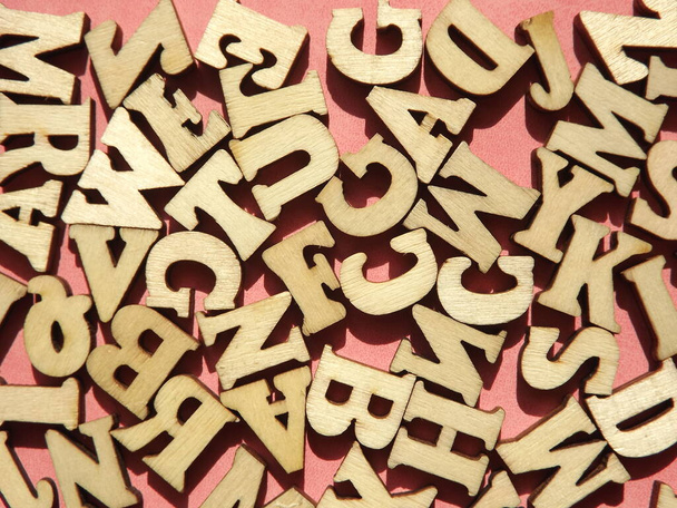 ピンクスエードを背景にした英語のアルファベットの木の文字 - 写真・画像