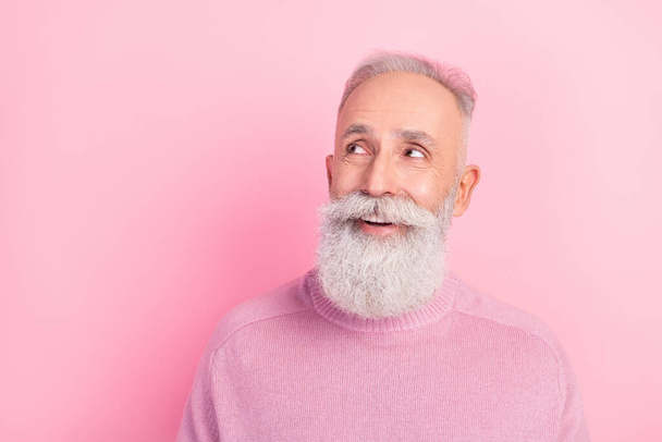 Photo of positive handsome grey hair old man look empty space wear pink sweater isolated on pastel color background - Photo, Image