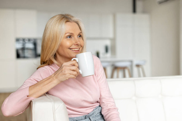 A calm and peaceful middle-aged woman takes a break, rests with a cup of hot tea - Фото, зображення