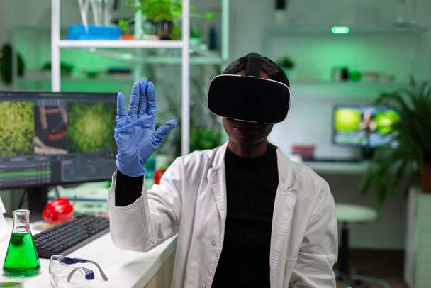 Biologiste afro-américaine femme portant casque de réalité virtuelle travaillant à l'expérience de microbiologie - Photo, image