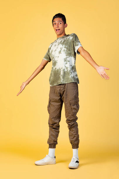 Portrait of young handsome boy, student in casual clothes posing isolated on yellow studio backgroud. Human emotions concept. - Φωτογραφία, εικόνα