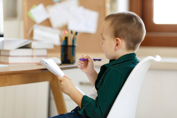 Uczennica uczy się w swoim pokoju. Chłopak używa laptopa i pisze w notatniku. Książki i tablet na stole. Ucz się w domu podczas krantyny. Zielony ekran - Zdjęcie, obraz