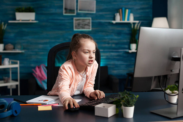Müde, übermüdet, kleines Kind blättert Schulinformationen auf dem Computer durch - Foto, Bild