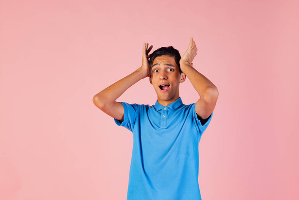Portrait of young teen boy, student wearing blue shirt posing isolated on pink studio backgroud. Human emotions concept. - Foto, imagen