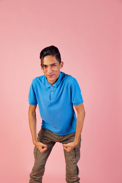 Portrait of young teen boy, student wearing blue shirt posing isolated on pink studio backgroud. Human emotions concept. - Foto, afbeelding