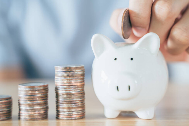 Closeup of man hand putting money coin into piggy bank for saving money. saving money and financial concept - Φωτογραφία, εικόνα