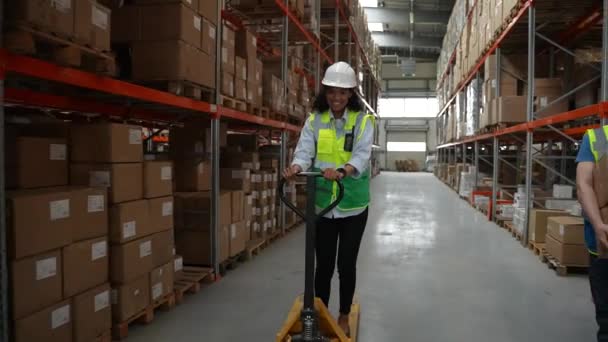 Cheerful woman riding pallet jack in warehouse - Footage, Video