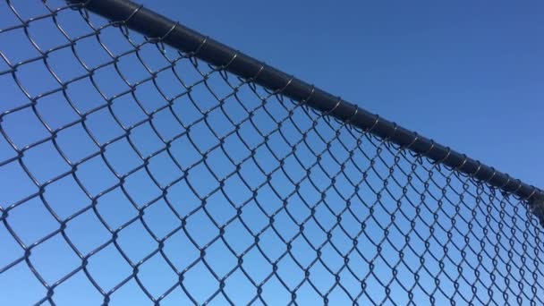Vista a basso angolo della rete metallica a catena ciclone recinzione contro il cielo blu sfondo astratto e texture - Filmati, video
