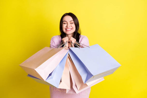 Photo of cute millennial lady hug bags like shopping wear sweater isolated on yellow color background - Φωτογραφία, εικόνα
