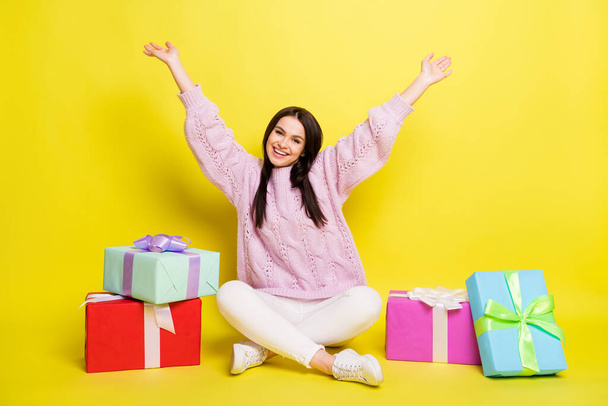 Full size photo of impressed millennial lady sit with present wear sweater pants isolated on yellow background - Photo, Image
