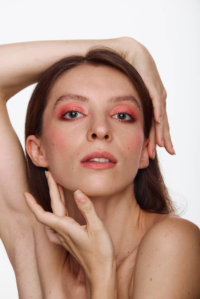 Όμορφο πρόσωπο νεαρής ενήλικης γυναίκας με καθαρό φρέσκο δέρμα και ροζ μακιγιάζ. Ομορφιά πορτρέτο του μελαχρινή με κόκκινα χείλη στέκεται σε λευκό φόντο αντίγραφο χώρου - Φωτογραφία, εικόνα