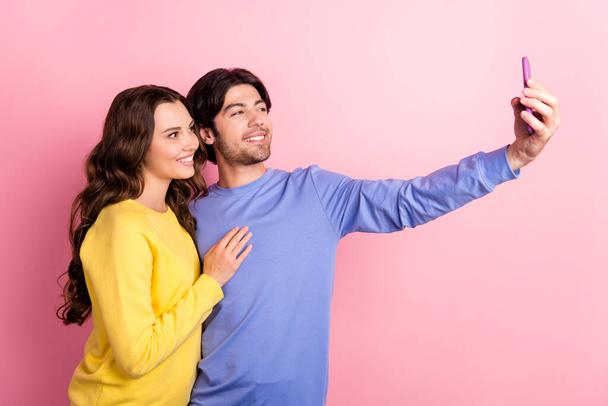 Photo of young lovely couple happy positive smile make selfie cellphone trip isolated over pink color background - Zdjęcie, obraz