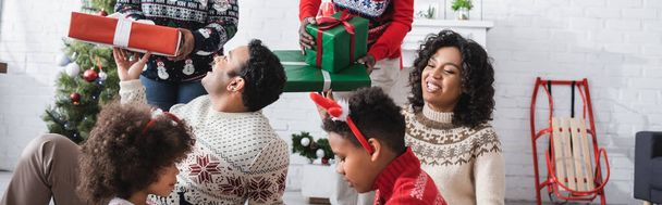 afro-amerikai család a nagyszülők közelében karácsonyi ajándékokkal a nappaliban, banner - Fotó, kép